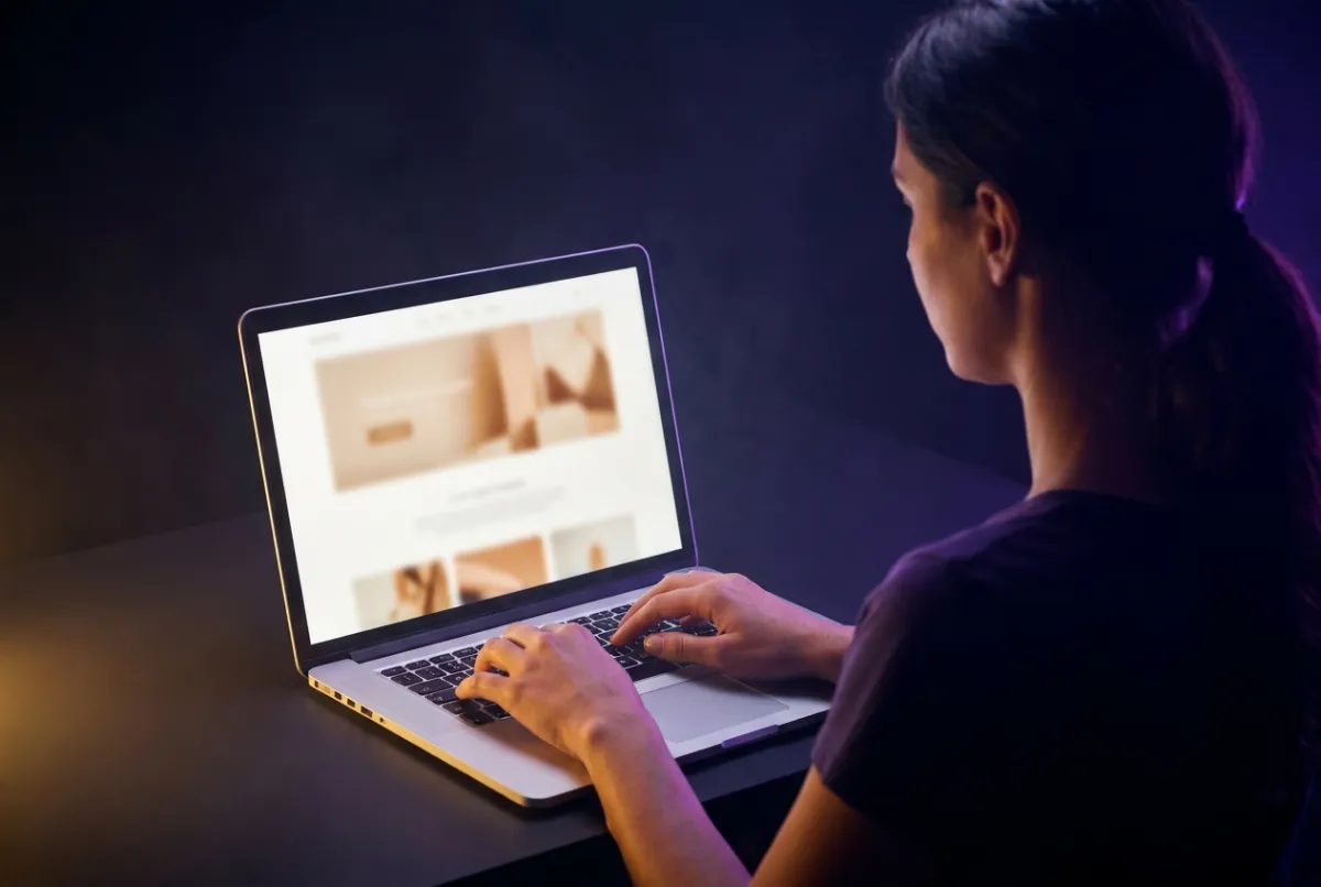 Over the shoulder of a woman typing as a one-page website takes shape on her screen
